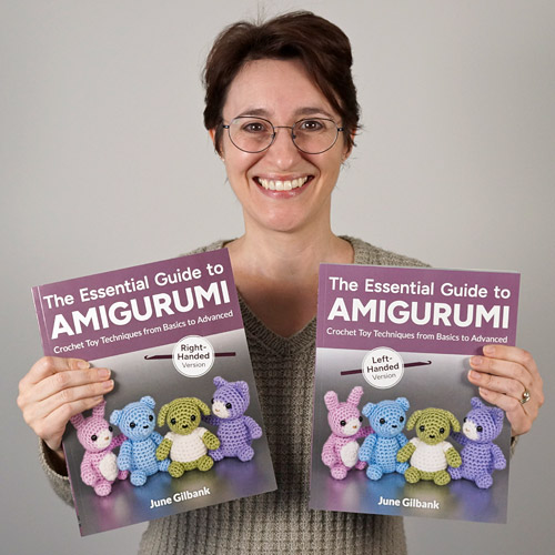 The Essential Guide to Amigurumi book by June Gilbank, right-handed and left-handed versions being held by the smiling author
