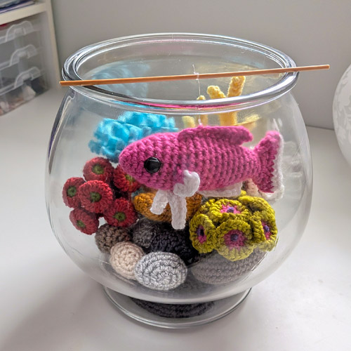 glass fishbowl with crocheted corals and a suspended tropical fish, all made from PlanetJune patterns
