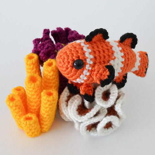 crocheted corals with an amigurumi clownfish on a white background